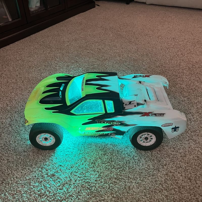 Short-course truck with green LED underglow lit up on the carpet